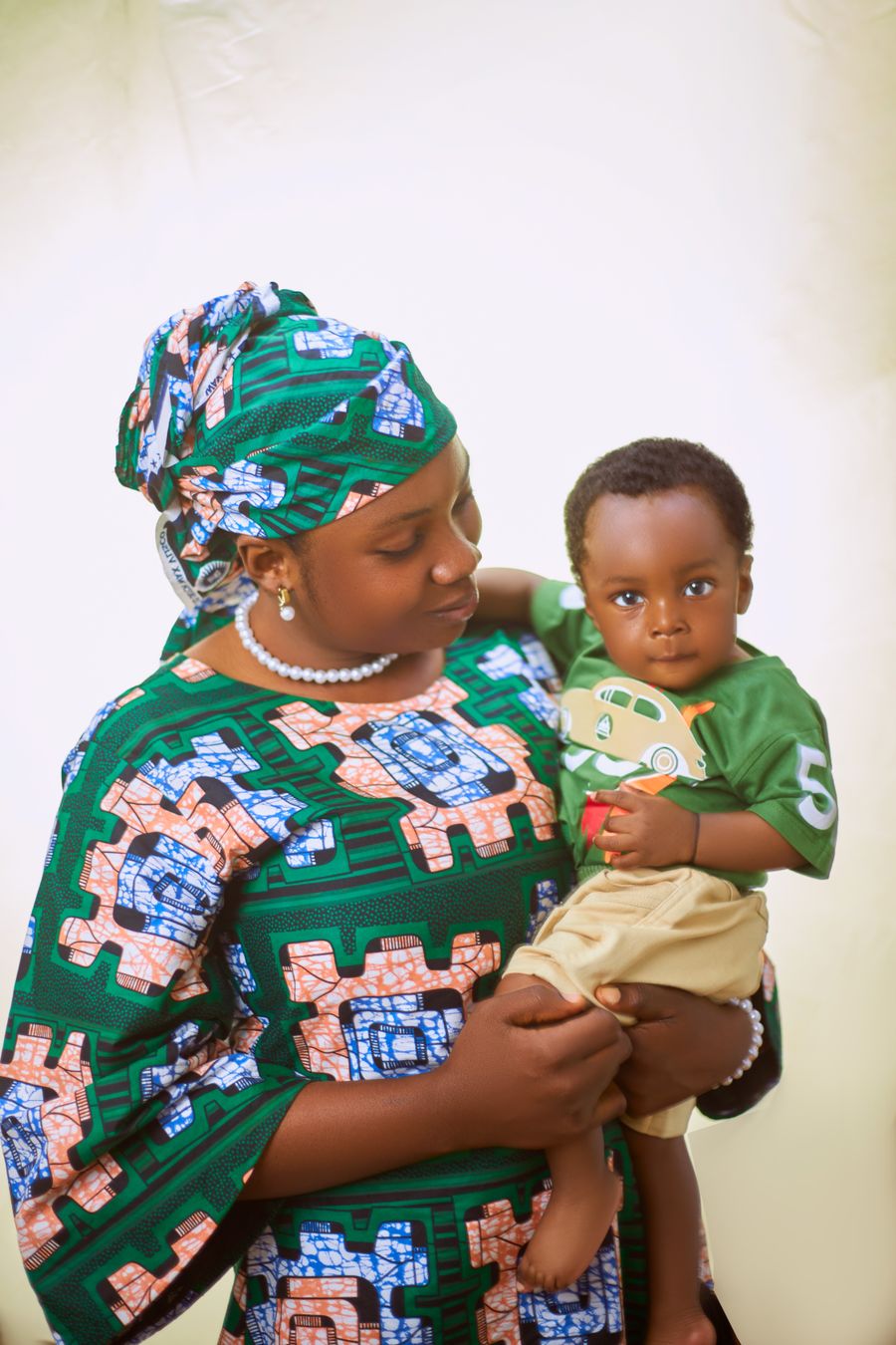 A mother in patterned dress holding her young child